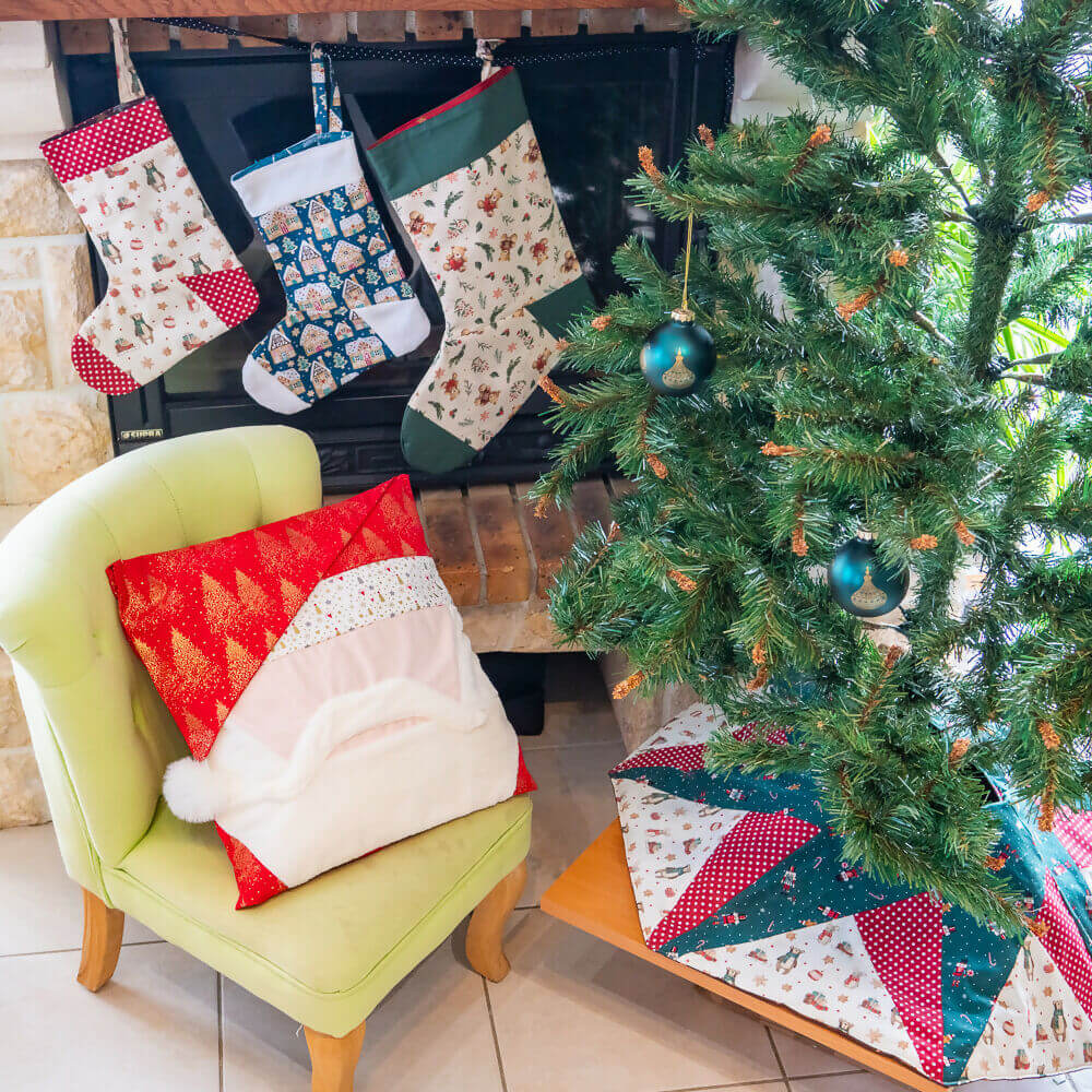 Chaussettes de Noël suspendues au-dessus d'un fauteuil vert, décorations festives autour d'un sapin de Noël.