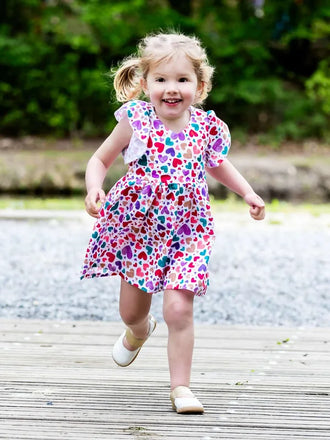 Petite fille souriante portant la robe colorée AIRELLE - La robe / blouse aux 1000 versions, patron de couture PDF à télécharger.