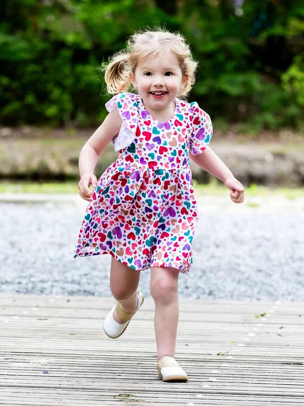 Petite fille souriante portant la robe colorée AIRELLE - La robe / blouse aux 1000 versions, patron de couture PDF à télécharger.