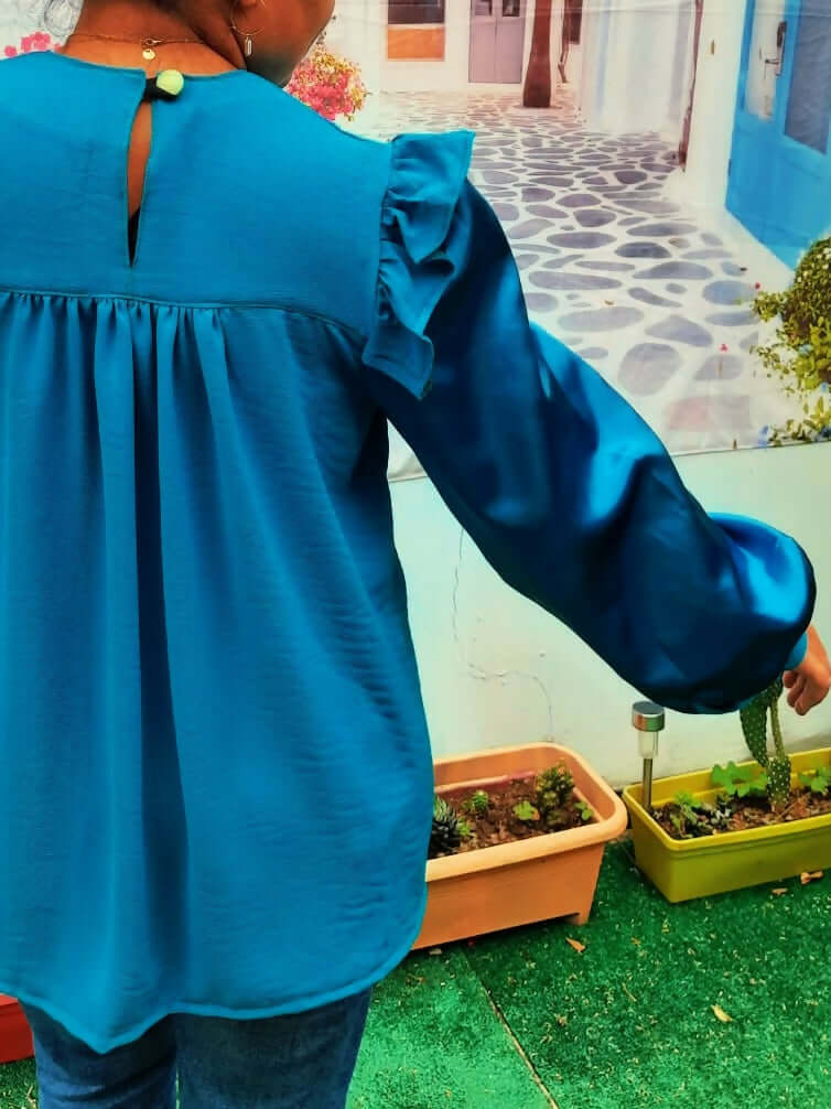 Blouse Idunn en satin bleu, avec volants, col arrondi et fente au dos. Patron PDF pour couture, tailles 36 à 50.