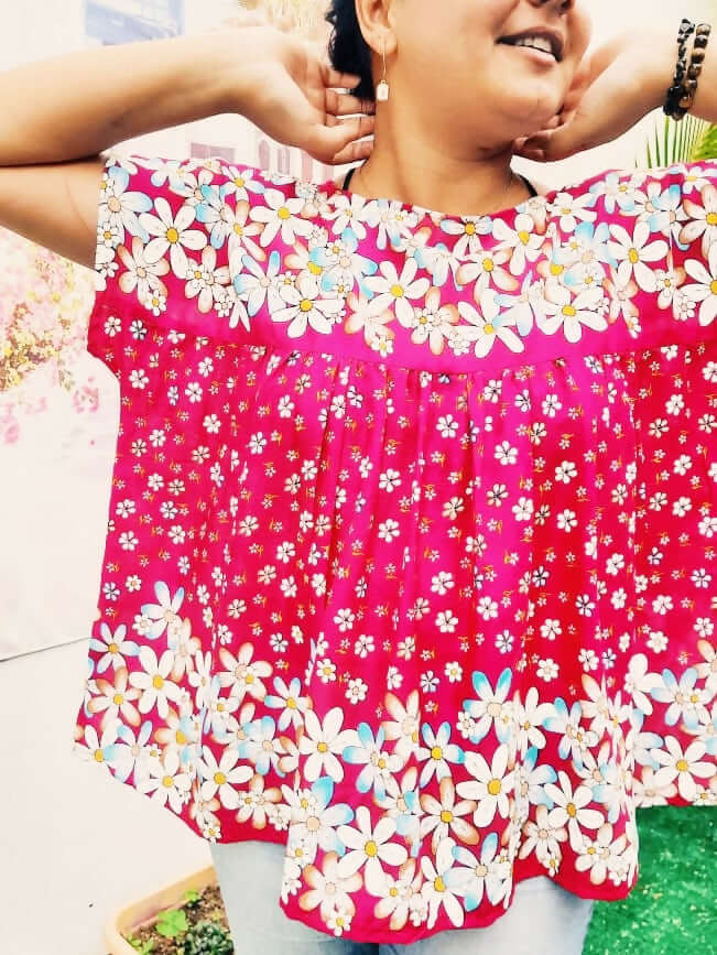 Femme souriante portant une blouse ample à fleurs roses, idéale pour un style décontracté en été.