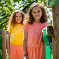 Enfants portant CRANBERRY - Le t-shirt pour toute la famille, patron de couture PDF à télécharger, dans un jardin ensoleillé.