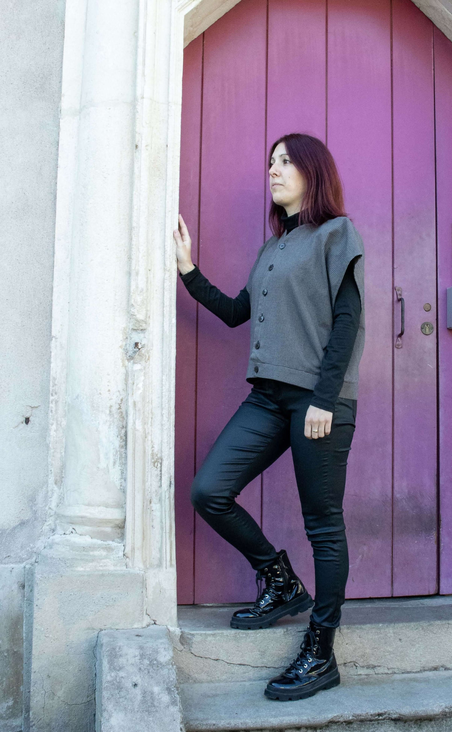 Femme portant un Gilet Emeraude, patron de couture PDF à télécharger, devant une porte violette.