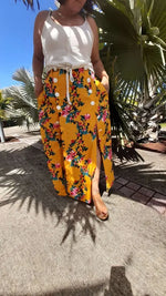 Femme portant la Jupe Astéria - T36 à 50 avec motif floral lumineux, patron de couture pdf à télécharger, sous un ciel ensoleillé.