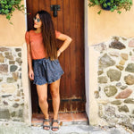 Femme portant Jupe / Short Bibiche - T34 à 48, devant une porte rustique, style décontracté. Patron de couture PDF à télécharger.