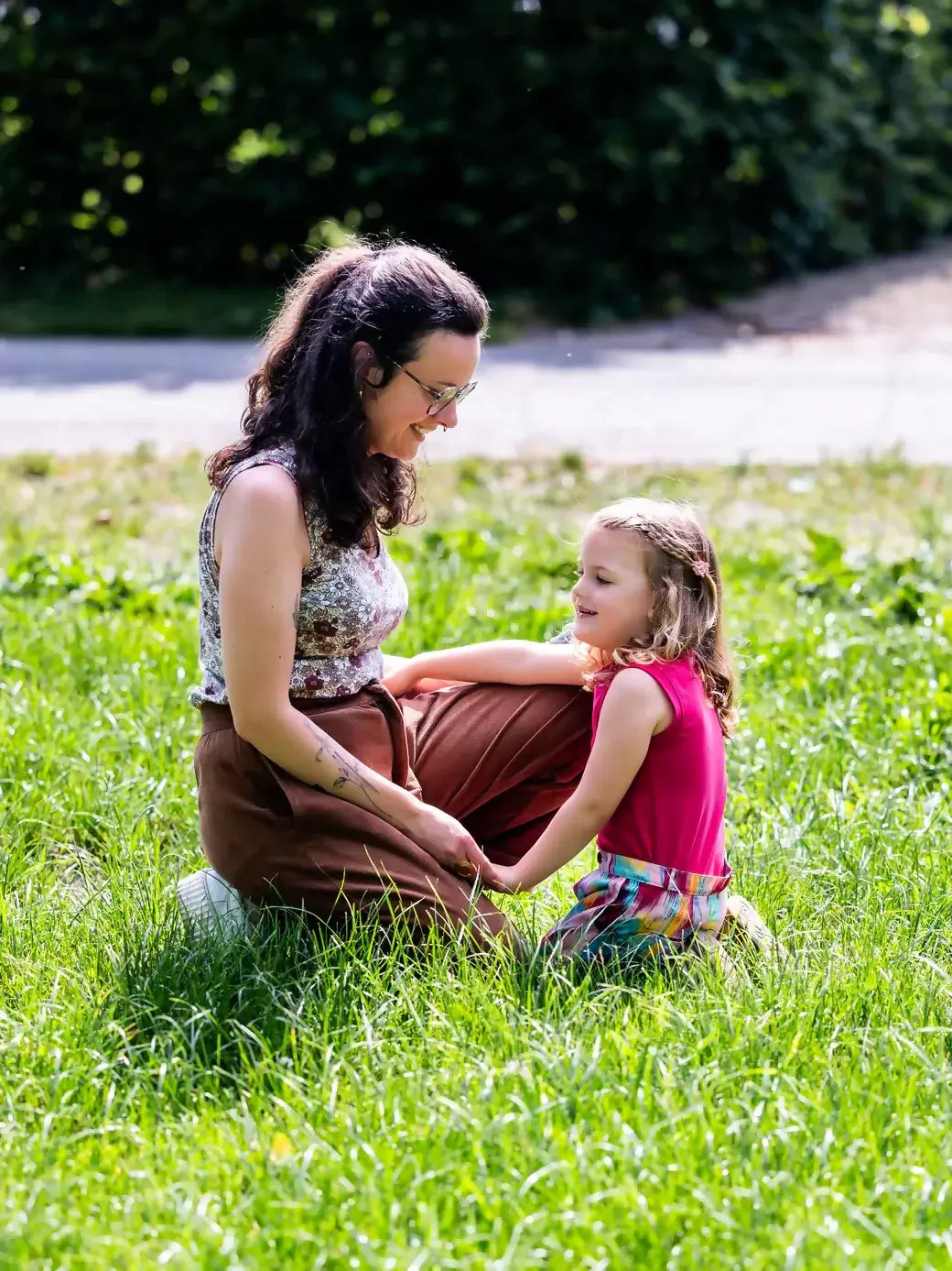 Une femme et une enfant assises sur l'herbe, profitant d'un moment ensemble en plein air.