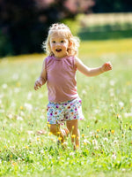 Enfant joyeuse portant un short à motif floral, courant dans un champ de fleurs. KUMQUAT - Le short / bermuda / pantalon, patron de couture pdf à télécharger.