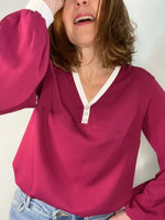 La blouse COLYNE du 34 au 48, en tissu rose avec encolure en V et boutons, style chic et sportif.