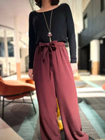 Femme portant la combi Blend Du 32 au 52, patron de couture pdf à télécharger, avec haut noir en jersey et bas fluide bordeaux.