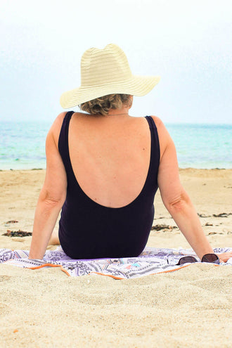 Personne portant un Maillot 1 pièce Mojito, assise sur la plage avec un chapeau, regardant la mer, patron de couture pdf à télécharger.
