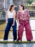 Deux femmes portant le NASHI - Le pantalon palazzo, un patron de couture PDF à télécharger, posent joyeusement sur un pont.