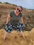Femme portant le Patron PDF Jupe Short LILAS & COQUELICOT, short fluide à fleurs bleues et orangées, en action sur la plage