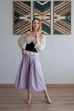 Femme portant un pantalon - XXS-XL - VINTAGE CADILAC avec un haut blanc et noir, sur un sol en bois.