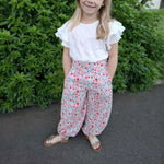 Enfant portant Pantalon Yasmine Enfants, patron de couture pdf à télécharger, avec coupe ample et ceinture haute, devant feuillage.