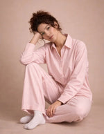Femme portant le Patron PDF Ensemble Blouse & Pantalon Pyjama ROSIE en coton à rayures roses, assise en coton blanc