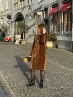 Femme portant le Patron PDF Robe Zoya en velours marron, vue de face en centre-ville, manches longues, coupe droite