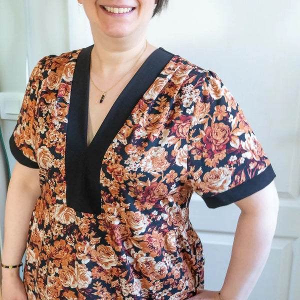 Femme portant le Patron PDF Robe courte Pomme Golden, manches courtes, col en V avec bande noire, imprimé floral orangé