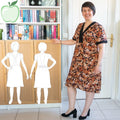 Femme portant le Patron PDF Robe courte Pomme Golden, col V noir, fleurs ocre et roses, vue de face en intérieur