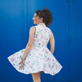 Femme portant le Patron PDF Robe Pelagia du 32 au 52, robe trapèze sans manches à fleurs multicolores, fond bleu