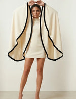 Femme portant le Patron PDF Robe MONA FLOW du 30 au 58, robe courte crème avec cape fluide à bordures noires