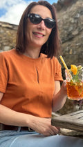 Femme portant le Patron PDF T-Shirt Femme Zestia en coton orange, en terrasse avec vue sur pierre