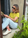Femme portant le Patron PDF T-Shirt Femme Zestia en jersey jaune citron, assise en terrasse