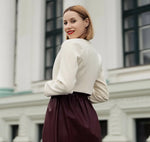 Femme portant le Patron PDF Veste Regina du XS au XL en crêpe blanc cassé, vue de dos devant une façade classique