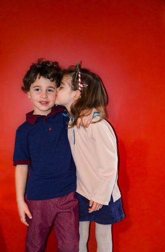 Enfants en Polo MARCOLOPO devant un mur rouge, modèle de patron de couture pdf à télécharger, mode enfant élégante et polyvalente.