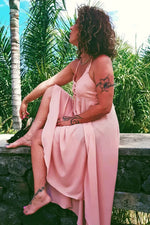 Femme portant la Robe Thoé - T36 à 50, coupe asymétrique, assise près des palmiers, patron de couture pdf à télécharger.