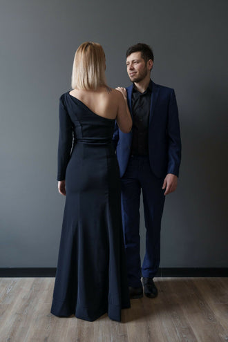 Deux personnes élégantes en tenue de soirée, femme regardant un homme, portant des vêtements formels noirs et bleus.