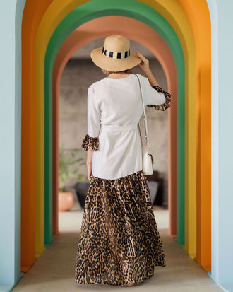 Femme portant une robe élégante avec un chapeau dans un couloir coloré.