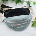 Sac banane Amaya en tissu côtelé, disponible en noir et bleu, idéal pour les accessoires quotidiens.