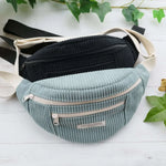 Sac banane Amaya en tissu côtelé, disponible en noir et bleu, idéal pour les accessoires quotidiens.