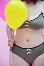 Modèle de bikini chocolat avec lanières, associé à des ballons colorés sur fond rose, stylé et confortable.