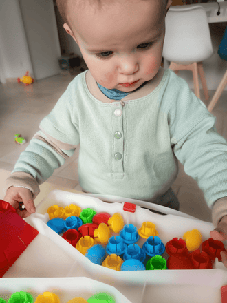 Enfant portant le Sweat MINI A - Patron PDF couture bébé du 12 mois au 4 ans, jouant avec des jouets colorés.