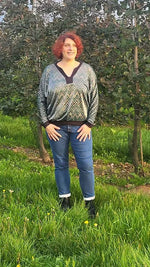 Femme portant un chandail à motifs dans un verger verdoyant.