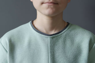 Jeune garçon portant un t-shirt vert clair, vue rapprochée de l'encolure et des épaules.