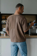 Homme portant un T-shirt homme du XXS au XXL - DOMINO dans une cuisine, consultable via patron de couture PDF à télécharger.