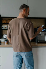 Homme portant un T-shirt homme du XXS au XXL - DOMINO dans une cuisine, consultable via patron de couture PDF à télécharger.