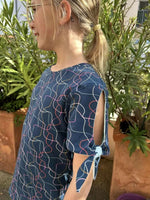 Top Chouchou pattern featuring a girl in a stylish, colorful blouse with tied sleeves outdoors.