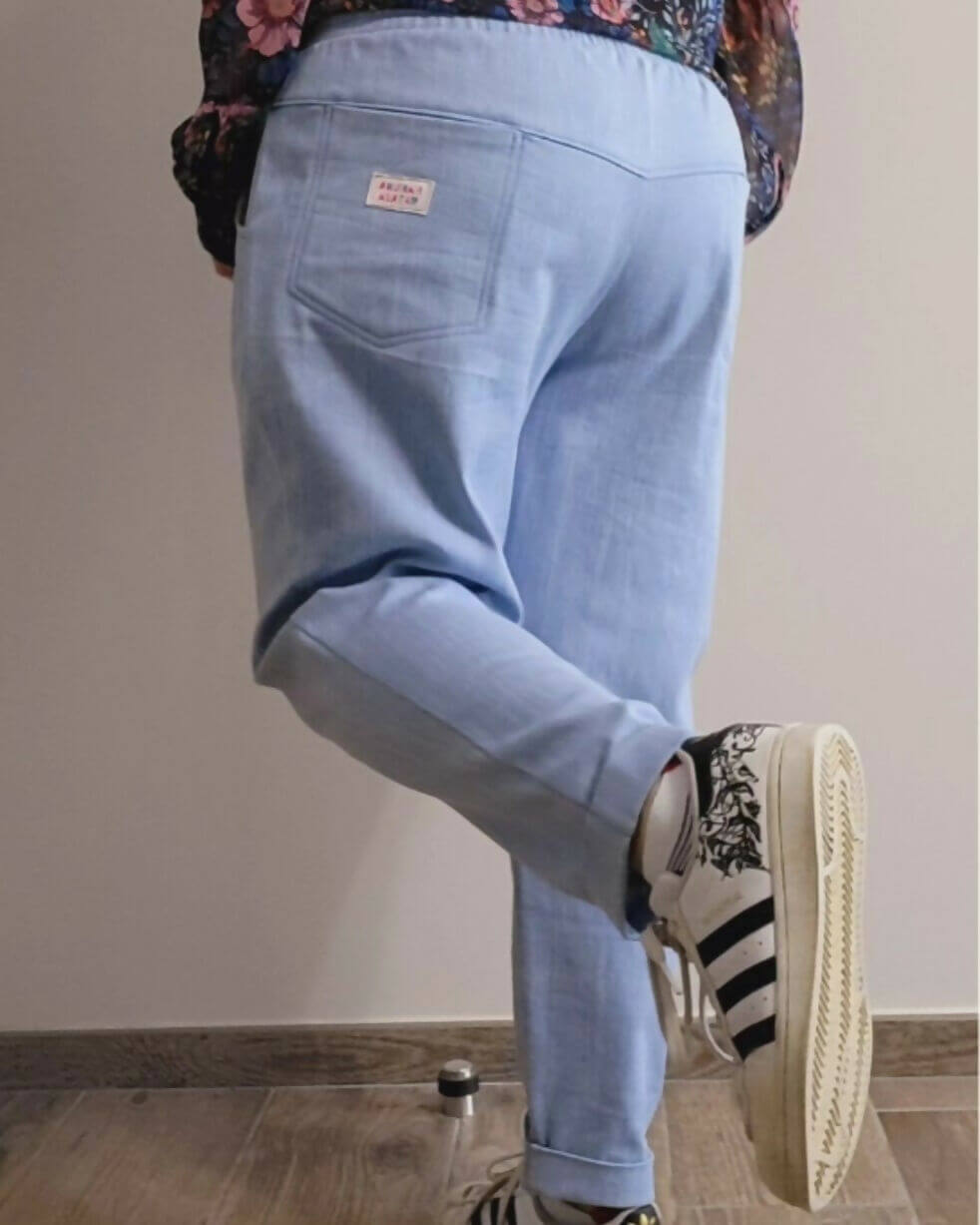 Pantalon sport chic en bleu, coupe carotte, parfait pour un look décontracté et élégant, porté avec des baskets.
