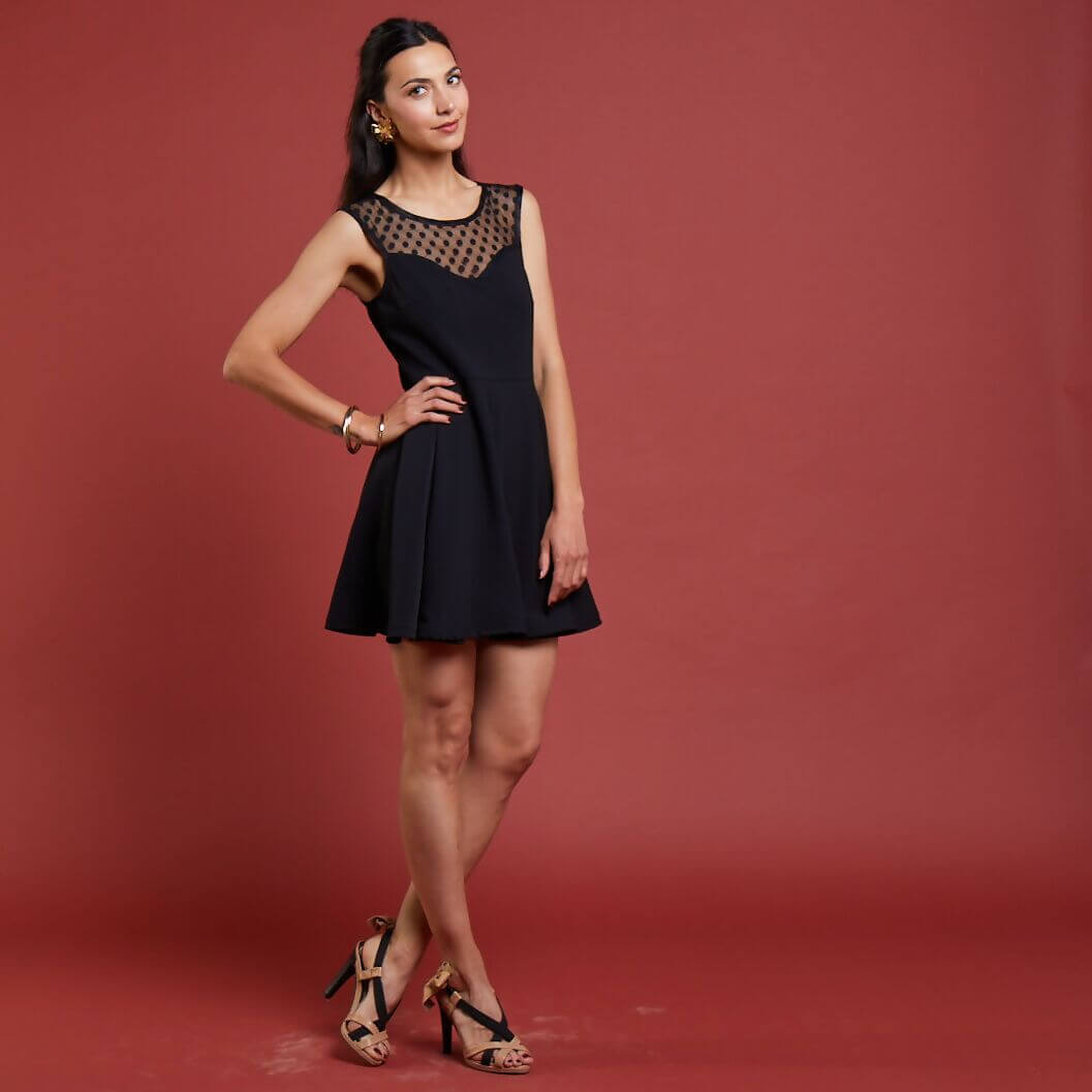 Femme portant la robe noire La Coquette, élégante avec col en dentelle, sur fond rouge, Collection Que la fête commence.
