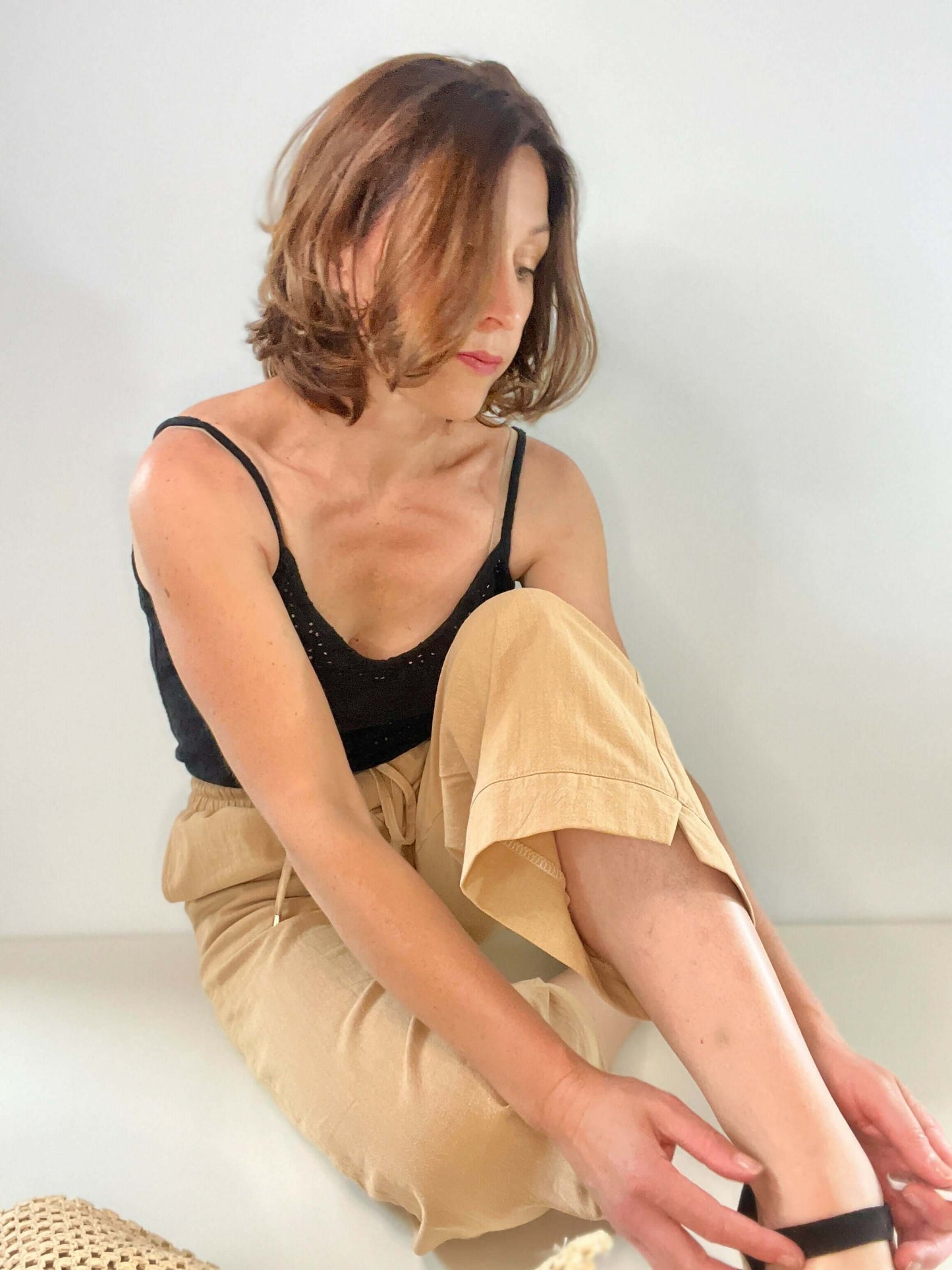 Femme en pantalon ample beige Springy, taille élastiquée, adoptant une pose décontractée sur fond neutre.