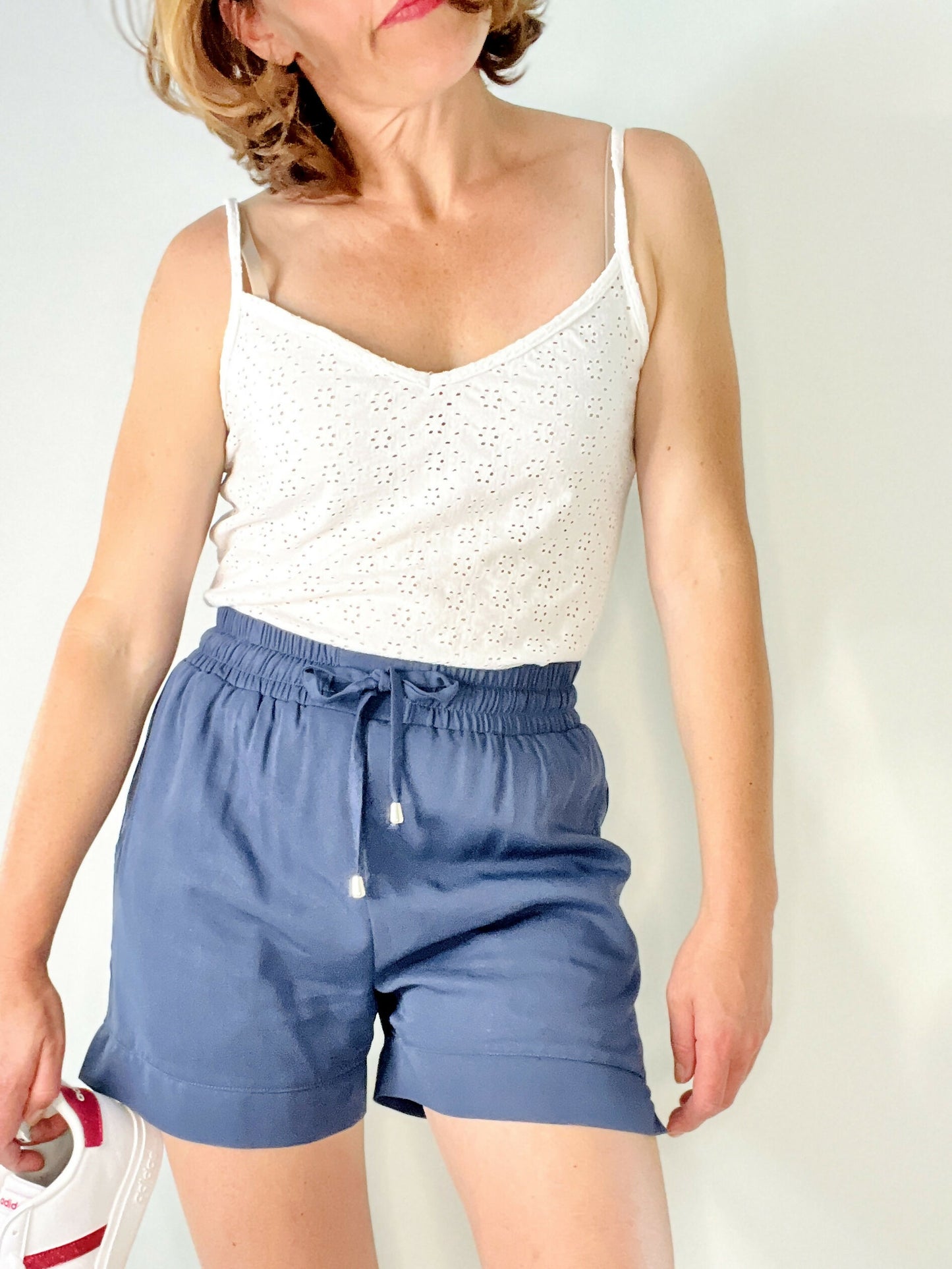 Femme portant un top blanc et un short bleu marine, style décontracté et confortable, prêt pour l'été.