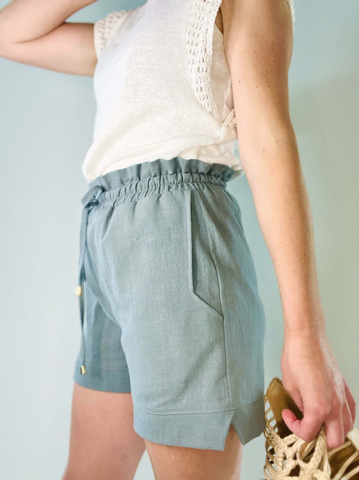 Femme portant un short bleu clair avec taille élastiquée et poches, idéal pour un look dynamique et confortable.