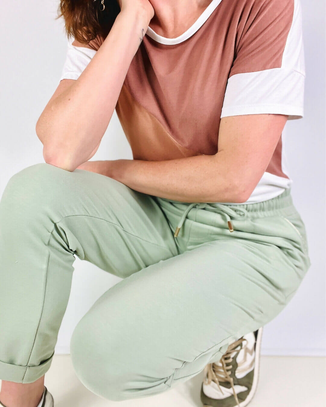 Femme vêtue d'un t-shirt dégradé et pantalon vert, illustrant une tenue décontractée et chic.