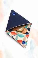 Porte-monnaie origami textile avec rabats triangulaires, boutons pression bleus et pièces, patron PDF gratuit.