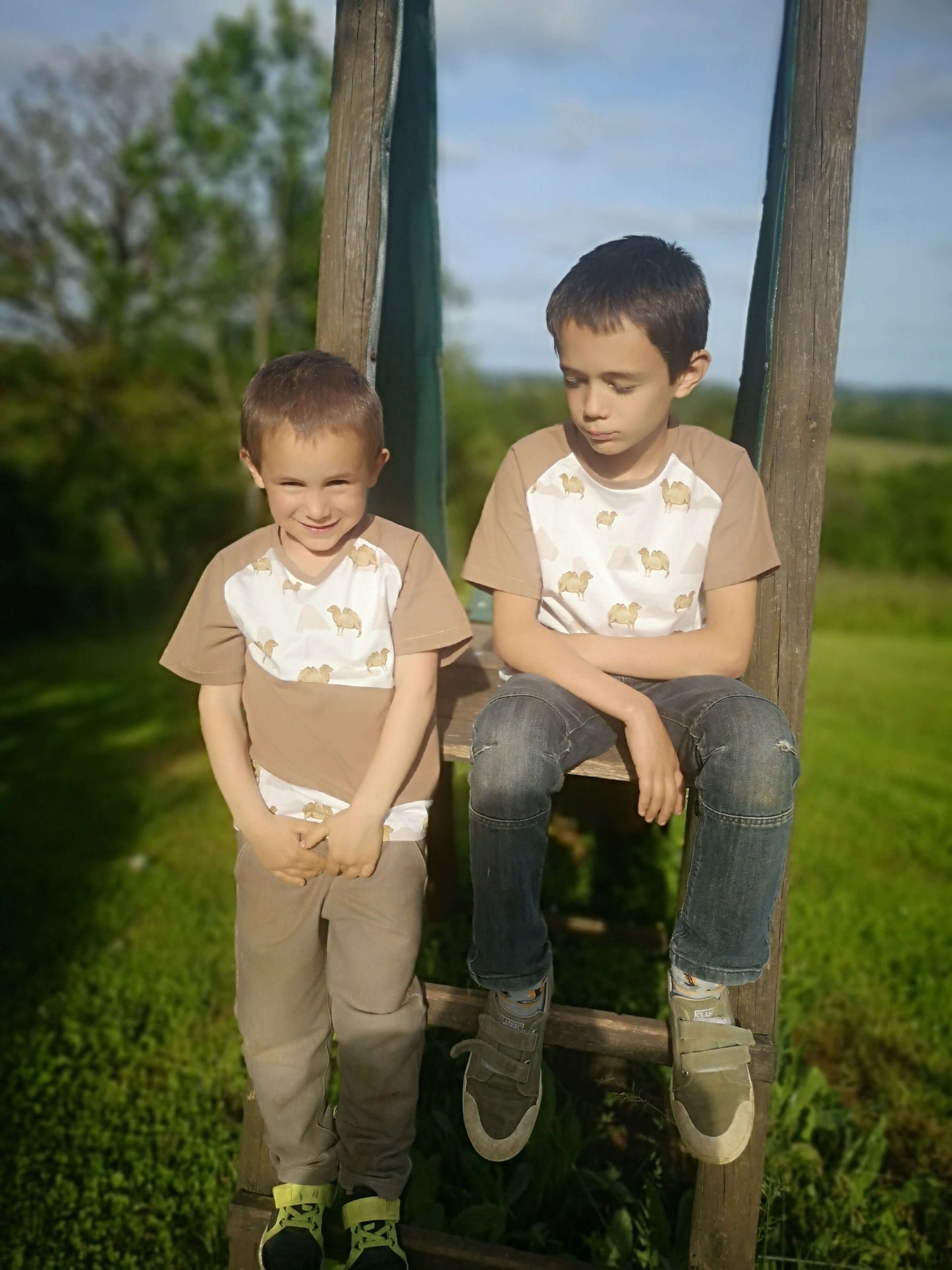 Deux garçons souriants portant des T-shirts Loulou en pleine nature, montrant le style multifacettes du patron.