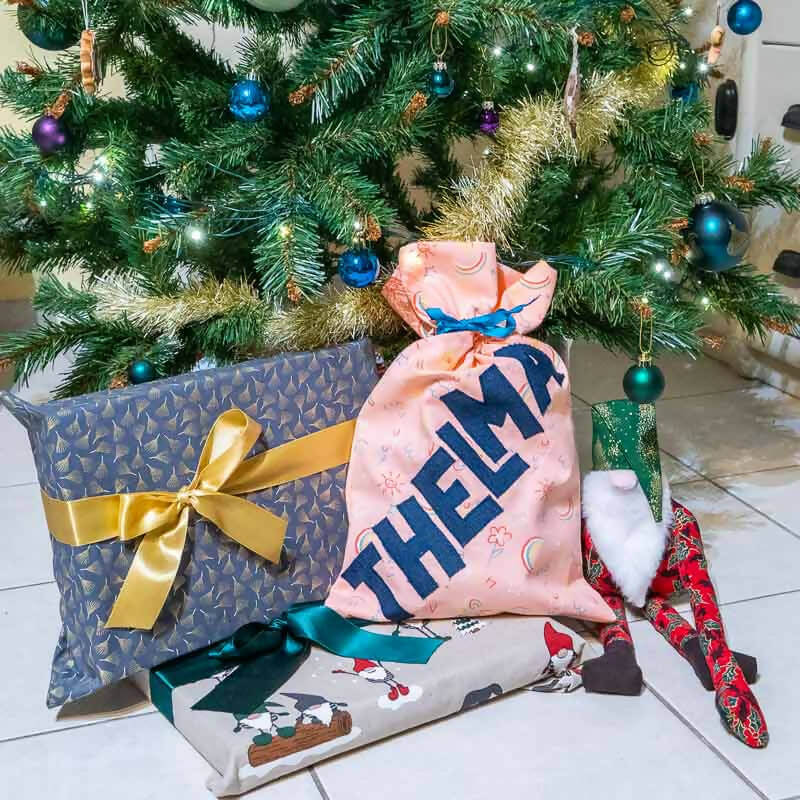 Cadeaux colorés et emballages créatifs sous un sapin de Noël, décorés de jolis plis et rubans.