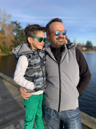 Père et fils portant Duo KEZIA - Doudoune sans manches mixte au bord d'un lac, idéale pour la mi-saison, patron de couture pdf à télécharger.